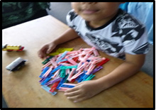 This is a picture of a young boy who has dozens of differently coloured pegs on the tabletop in front of him