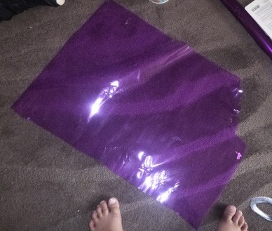 This is a picture of a purple rectangle of cellophane - approximately 1 meter by 50cm - placed on grey carpet