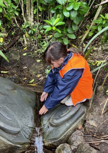 A photo of a child touching water flowing through a large carved stone